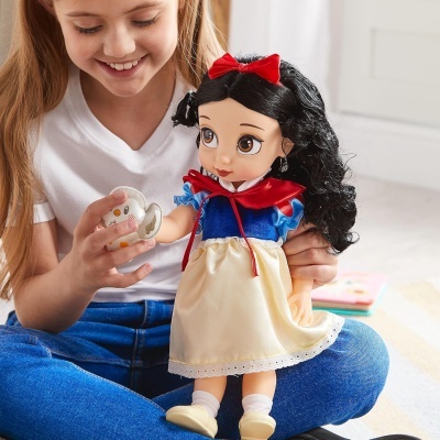 Boneca Branca de Neve com vestido colorido e cabelo preto com laço vermelho, em ambiente interior com criança
