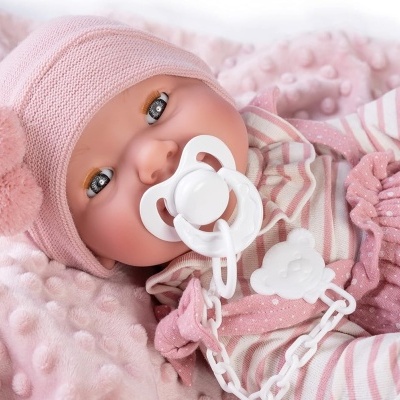 Boneca bebé com roupa rosa e chupeta deitada sobre manta rosa
