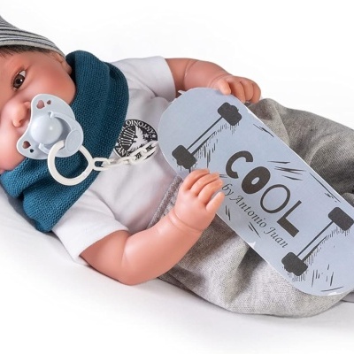 Boneca bebé com roupa azul, branca e cinzenta e placa com a palavra COOL
