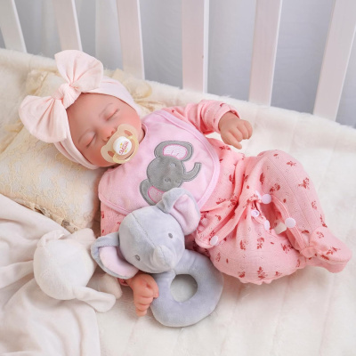 Boneca bebé com roupa cor-de-rosa e chapéu com laço no berço branco