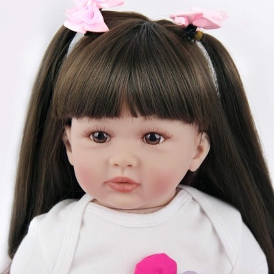 Boneca com cabelo castanho preso com fitas rosas e roupa branca com flores coloridas