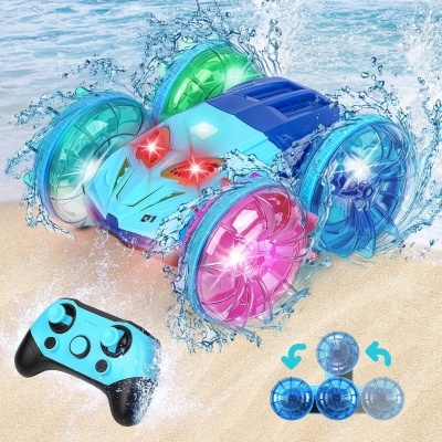 Carro de brinquedo azul com rodas coloridas na areia e controle remoto azul e preto