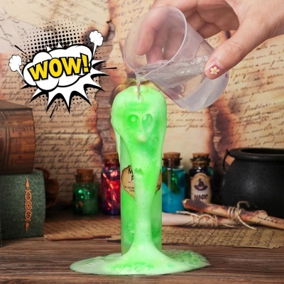 Vela verde brilhante a derreter com rosto fantasmagórico em fundo com livros antigos e garrafas