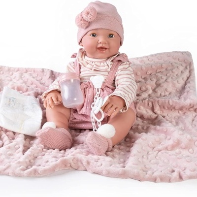 Boneca bebé vestida com pijama riscado e acessórios, sentada num cobertor rosa