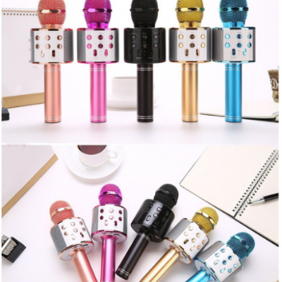 Cinco microfones karaokê coloridos sobre mesa branca com caderno, caneta e xícara