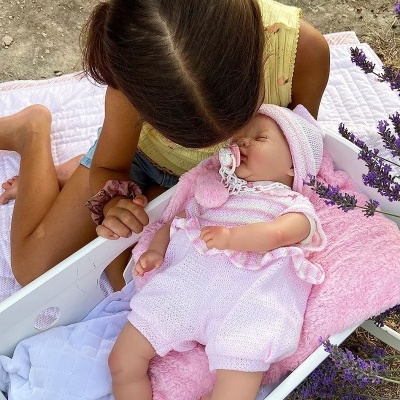 Bebé com roupa rosa em cama branca ao ar livre com criança ao lado