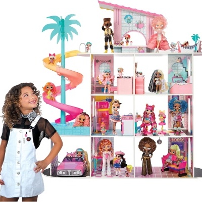 Casa de bonecas branca com escorrega espiral rosa, várias bonecas coloridas e acessórios, menina ao lado olhando para a casa.