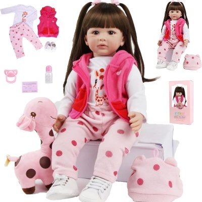 Boneca bebé realista com roupas rosas e acessórios, sentada com peluche de girafa rosa.