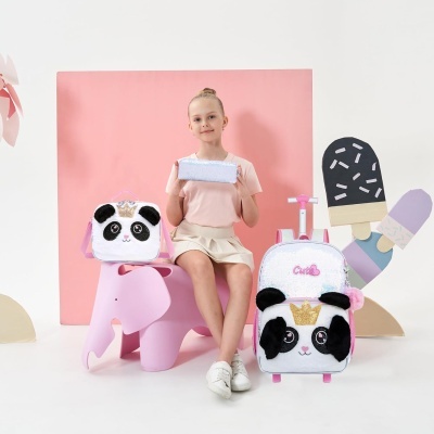 Mochila e bolsa térmica com tema de panda, branca, preta e rosa, exibidas numa sessão fotográfica com fundo rosa.