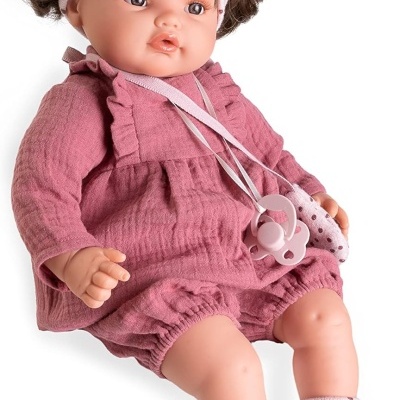 Boneca bebé vestida de rosa com faixa de cabeça e botins com pintas.