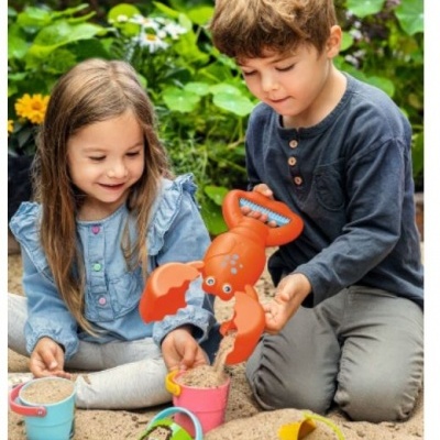 Crianças a jogar na areia com baldes e pá lagosta coloridos