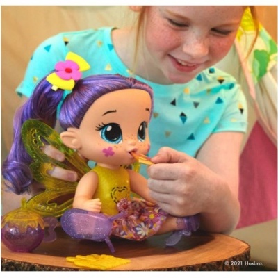 Boneca de fada com cabelo roxo sendo alimentada por criança