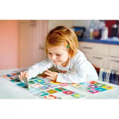 Criança a jogar jogo de cartas coloridas numa mesa branca