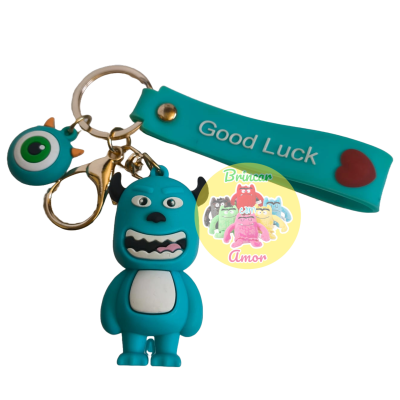 Porta-chaves com figura de monstro azul, pendente azul-verde e tira azul com 'Good Luck'