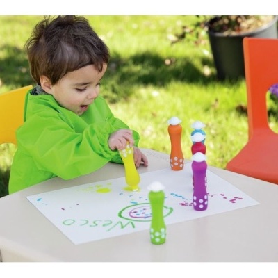 Criança a desenhar numa mesa ao ar livre com marcadores coloridos tipo boneco