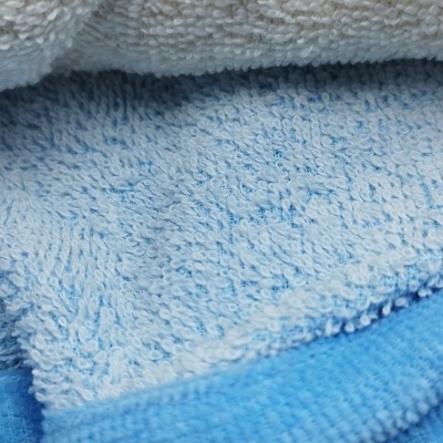 Toalhas empilhadas de cores azul claro, azul escuro e branco com textura felpuda