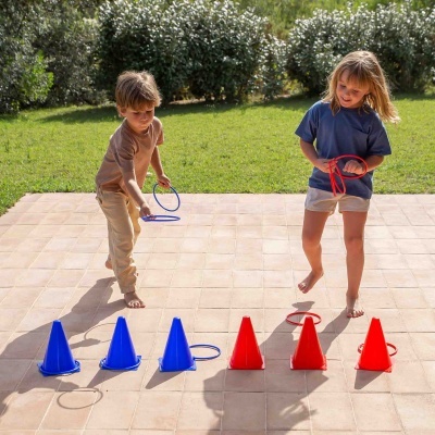 Crianças a jogar com cones e anéis de plástico azul e vermelho num pátio ao ar livre