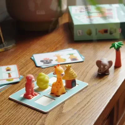 Jogo infantil de tabuleiro com peças de animais e objetos coloridos sobre uma mesa de madeira