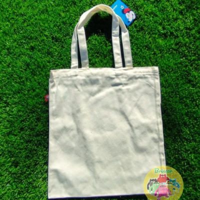 Saco de tecido branco com alças sobre relva artificial verde