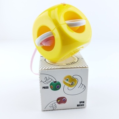 Brinquedo amarelo em cubo com esferas internas sobre caixa com instruções