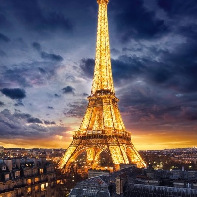 Torre Eiffel iluminada à noite com edifícios antigos em primeiro plano
