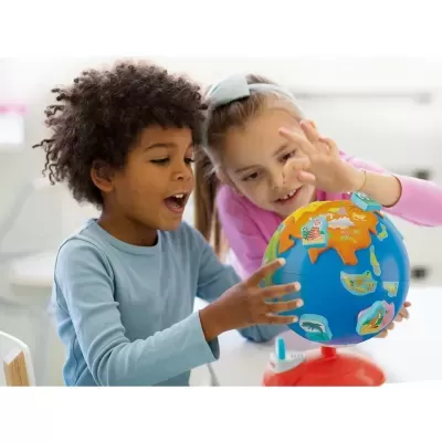 Crianças a brincar com globo terrestre colorido em ambiente interior.