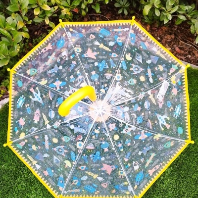 Guarda-chuva transparente com padrão colorido e borda amarela sobre relva