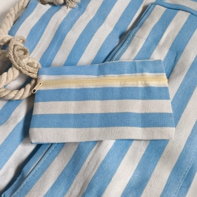 Toalha ou nincho de praia azul e branca às riscas com pequeno saco e corda para transporte