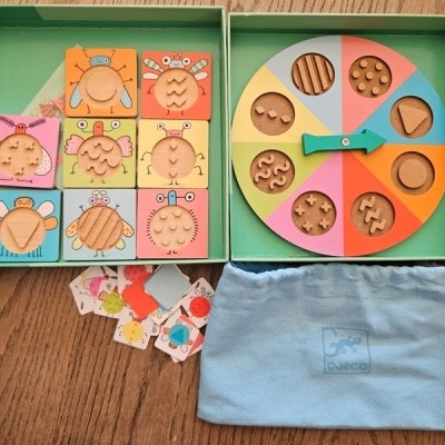 Jogo educativo com blocos de madeira quadrados coloridos e disco tátil em caixa verde