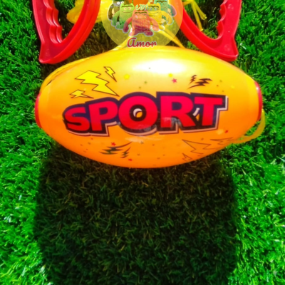 bola amarela com palavras SPORT e dois objetos vermelhos sobre relva verde
