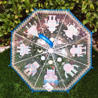 Guarda-chuva transparente com padrão de robôs coloridos e borda azul em relva.