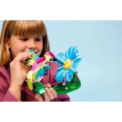 Menina segura construção LEGO de pássaro e flor azul.