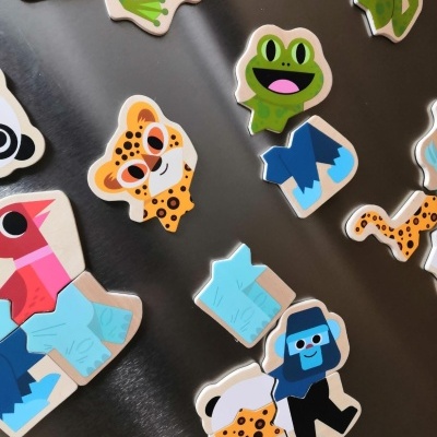 Peças de puzzle de madeira com figuras coloridas de animais e pessoas sobre uma superfície metálica