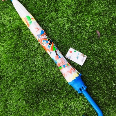 Guarda-chuva fechado com cabo azul e padrão colorido sobre relva