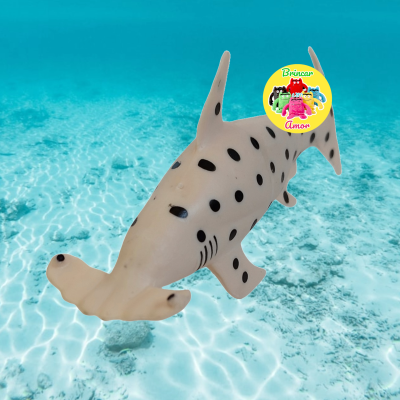 Figura de tubarão-martelo branca com manchas pretas em fundo aquático azul claro.