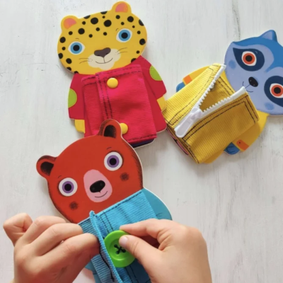 Três brinquedos de pelúcia de animais com casacos coloridos e diferentes fechos, em fundo branco