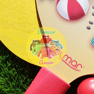 Raquete colorida com cabo vermelho e desenhos lúdicos sobre relva verde