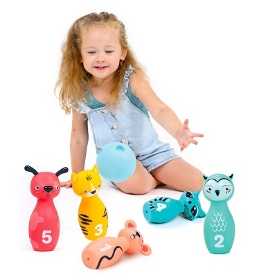 Criança com bonecos de boliche coloridos e bola azul claro sobre fundo branco