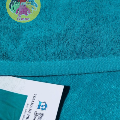 Toalha de banho azul-turquesa com etiqueta Perfect Beach em fundo azul