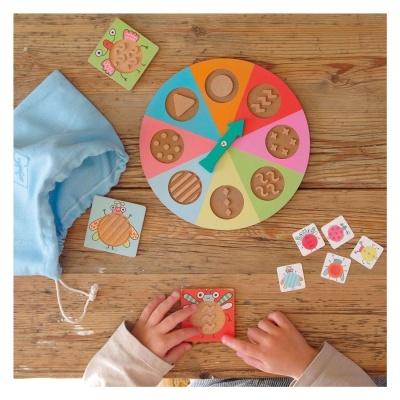 Brinquedo educativo de madeira com disco giratório colorido e cartas com texturas e desenhos de insetos.