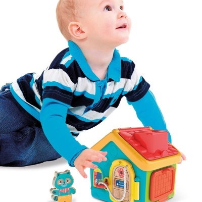 Criança a brincar com brinquedo colorido em forma de casa e figura de coruja