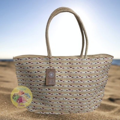 Saco de praia colorido com pegas de corda na areia com mar ao fundo