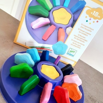 Lápis de cera coloridos em suporte azul com embalagem ao fundo