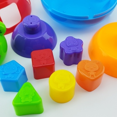 Brinquedos de plástico coloridos com formas geométricas e cabeça de sapo