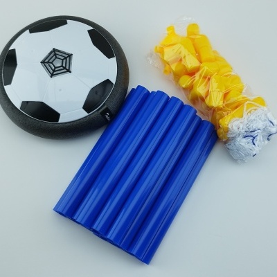 Disco voador preto e branco, cilindros azuis e peças amarelas em saco transparente sobre mesa branca