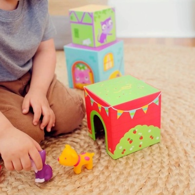 Criança a brincar com cubos e brinquedos de animais coloridos no chão com tapete bege