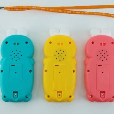 Três dispositivos eletrónicos em forma de coelho azul, amarelo e rosa com fita laranja