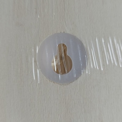 Superfície de madeira clara com orifício em forma de pingo e proteção plástica circular