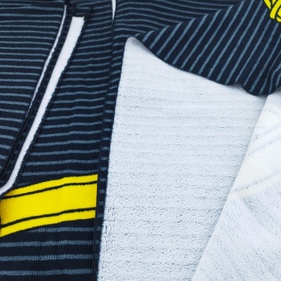 Toalhas dobradas com padrão de riscas finas em azul escuro, branco e amarelo.