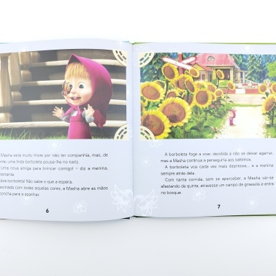 Livro infantil aberto com ilustrações da Masha, uma menina com capuz rosa e uma borboleta, texto em português e fundo com escadas de madeira e girassóis.